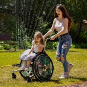 Kinderrollstuhl Mädchen Spaß lachen Wasser Rollstuhl